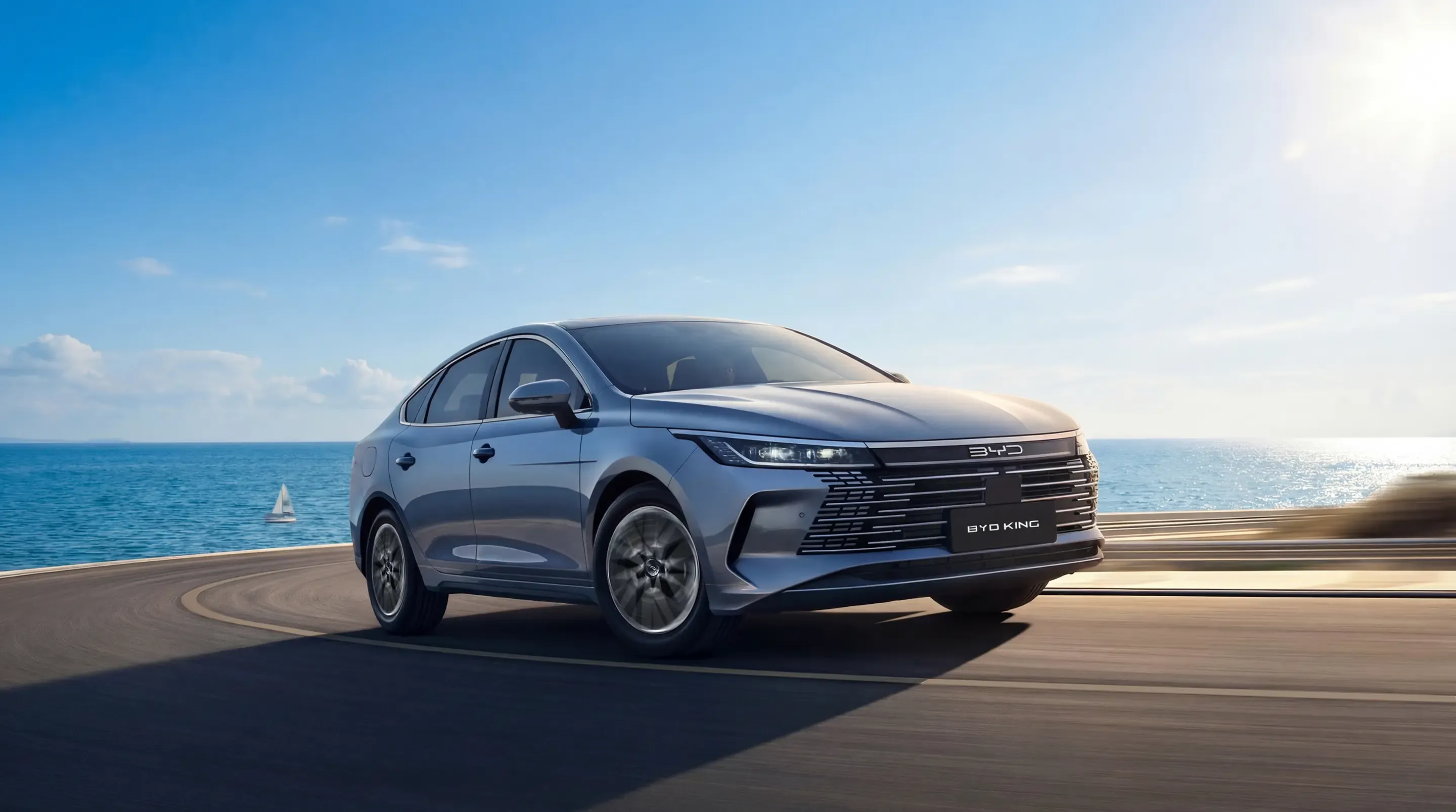 BYD King prata em movimento numa estrada à beira-mar